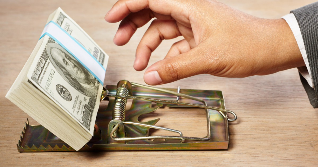 Mano tomando unos billetes colocados sobre una trampa