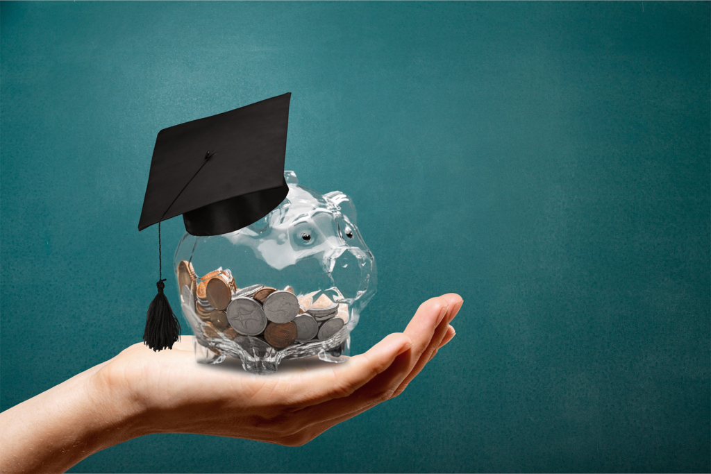 Birrete de graduación sobre una hucha llena de monedas