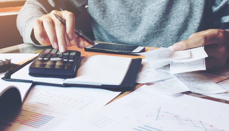 Persona haciendo cálculos con una calculadora y documentos